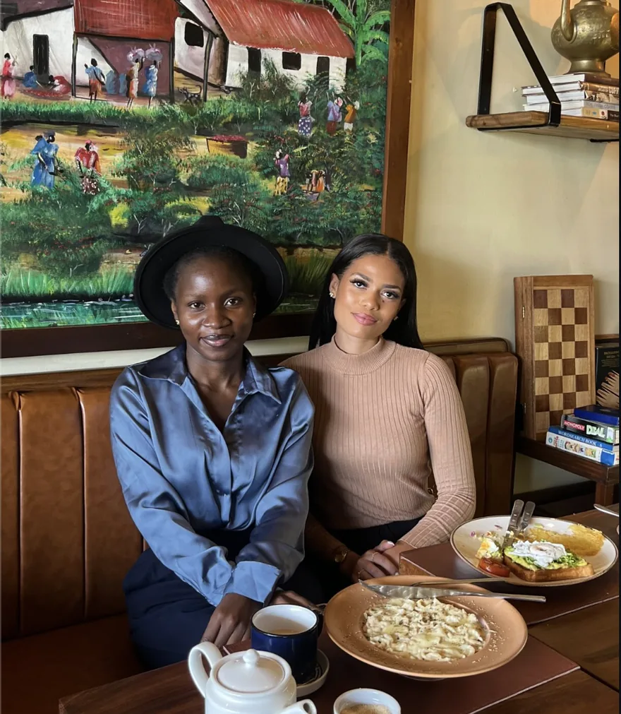 Two guests sharing breakfast at Coffee Culture beneath the painted Tanzanian wall art