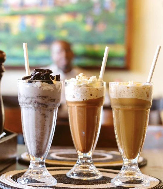 Three iced coffee drinks topped with cream in tall glasses